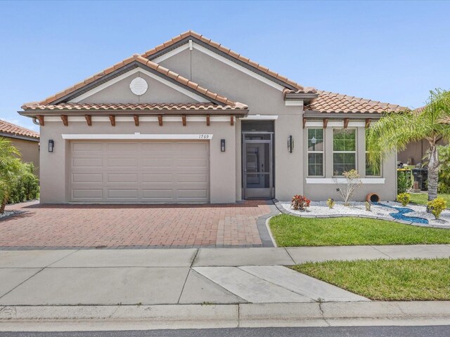 1709 Benoit Ter, Davenport, FL 33837 - mediterranean / spanish home featuring an attached garage, decorative driveway, stucco siding, and a tiled roof
