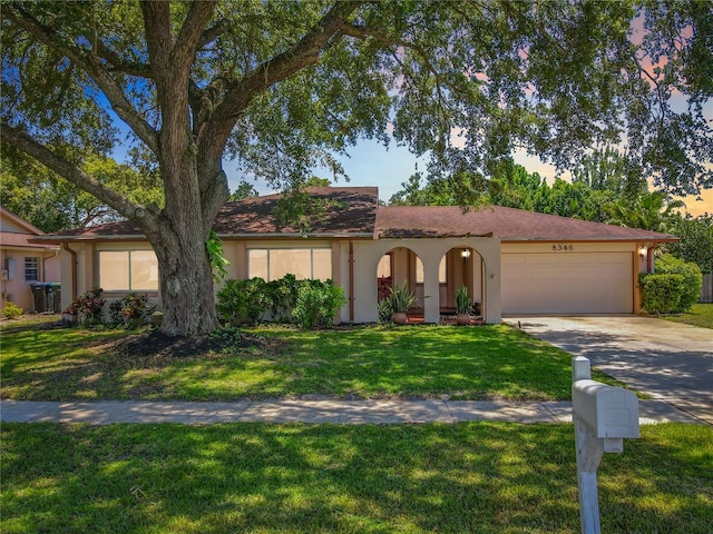 8346 Mattituck Cir, Orlando, FL 32829 - view of front of property with a garage, stucco siding, concrete driveway, and a front lawn