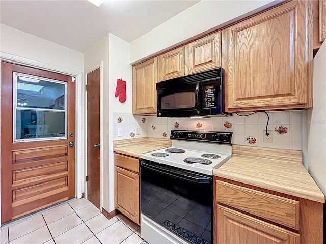 8346 Mattituck Cir, Orlando, FL 32829 - kitchen with electric range, black microwave, light countertops, backsplash, and light tile patterned floors