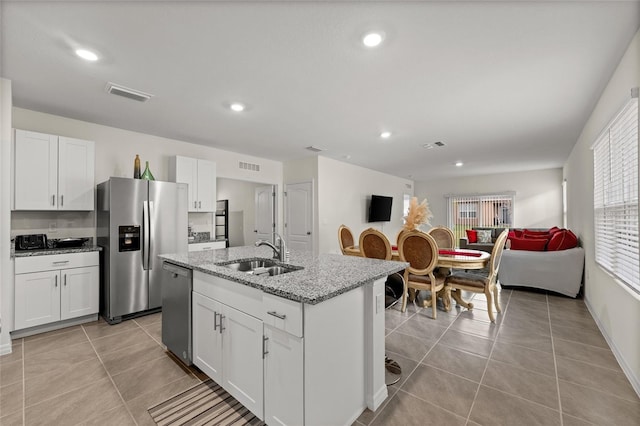 1792 Bull Hill Rd, Kissimmee, FL 34744 - kitchen featuring appliances with stainless steel finishes, white cabinetry, a kitchen island with sink, light stone counters, and recessed lighting