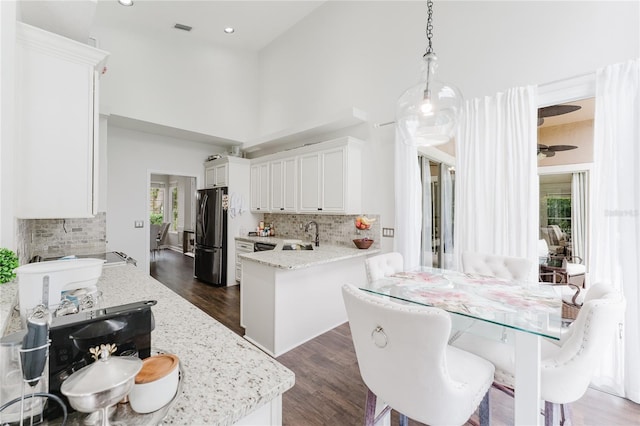 9285 Wickham Way, Orlando, FL 32836 - kitchen with freestanding refrigerator, decorative backsplash, dark wood-style floors, light stone counters, and a towering ceiling