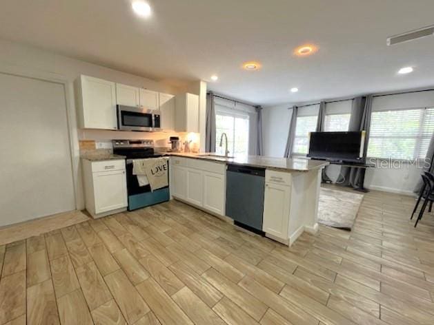 9148 Oakwood Dr, Lake Wales, FL 33898 - kitchen with stainless steel appliances, a peninsula, white cabinets, and recessed lighting
