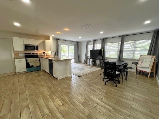 9148 Oakwood Dr, Lake Wales, FL 33898 - kitchen featuring appliances with stainless steel finishes, white cabinetry, a peninsula, light wood-style flooring, and recessed lighting