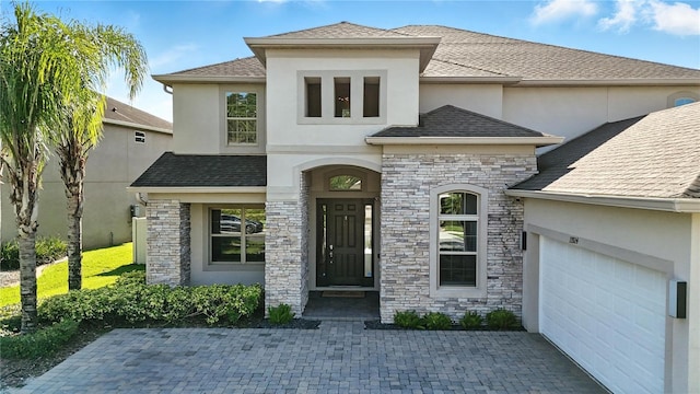 13924 Jomatt Loop, Winter Garden, FL 34787 - view of front of house featuring stucco siding, stone siding, a garage, and a shingled roof