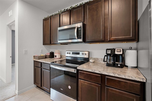 1351 Fox Squirrel Dr, Davenport, FL 33897 - kitchen featuring stainless steel appliances, dark brown cabinets, light countertops, and light tile patterned floors