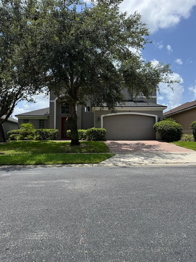 5040 Rock Rose Loop, Sanford, FL 32771 - obstructed view of property with driveway, an attached garage, a front lawn, and stucco siding