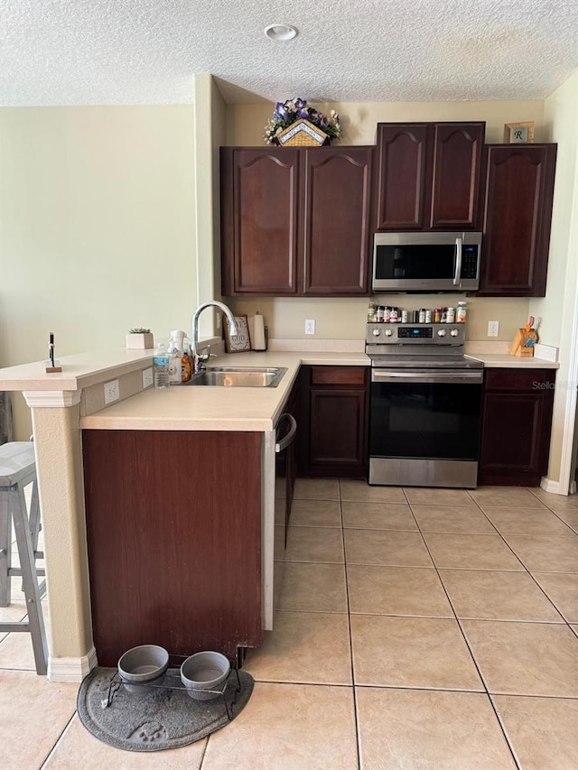 5040 Rock Rose Loop, Sanford, FL 32771 - kitchen with stainless steel appliances, a textured ceiling, light countertops, light tile patterned floors, and dark brown cabinetry