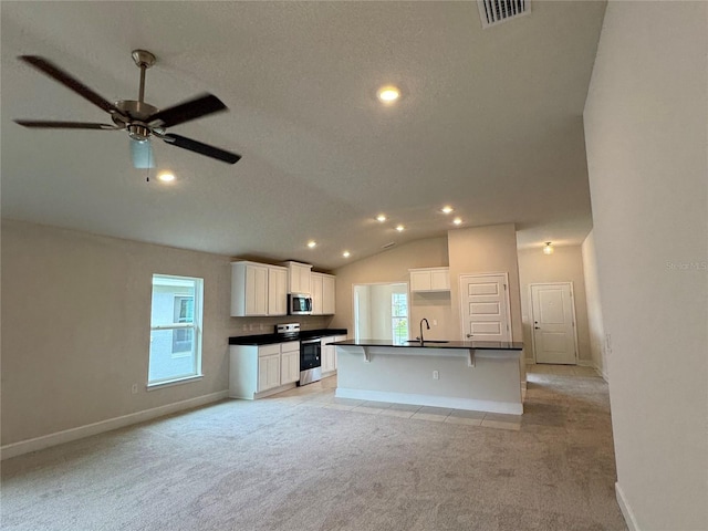 3891 Sagefield Dr, Harmony, FL 34773 - kitchen featuring dark countertops, stainless steel appliances, light carpet, lofted ceiling, and ceiling fan