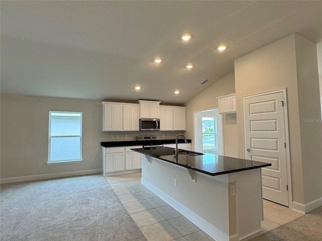 3891 Sagefield Dr, Harmony, FL 34773 - kitchen with stainless steel appliances, dark countertops, recessed lighting, a kitchen island with sink, and white cabinetry