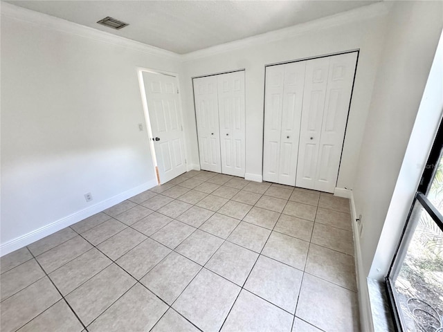 508 Sandtree, Palm Beach Gardens, FL 33403 - unfurnished bedroom featuring multiple closets, light tile patterned floors, and crown molding