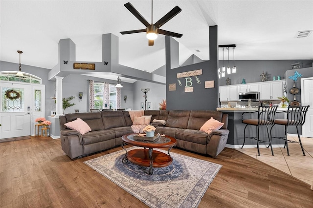 544 Lake Sumner Dr, Groveland, FL 34736 - living room featuring ceiling fan, vaulted ceiling, ornate columns, and light wood-type flooring