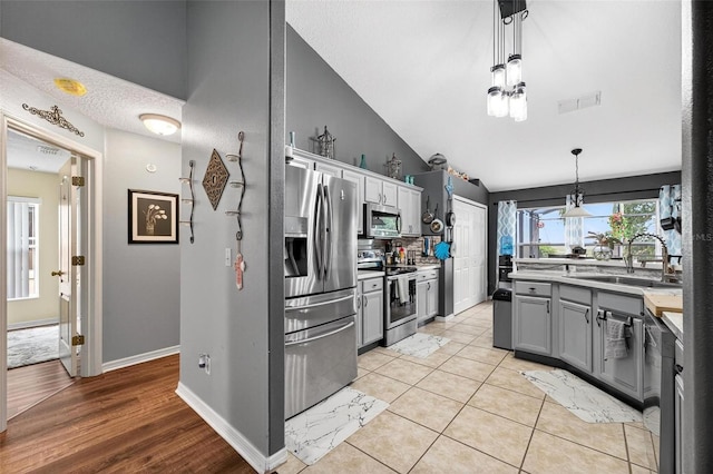 544 Lake Sumner Dr, Groveland, FL 34736 - kitchen with appliances with stainless steel finishes, gray cabinets, hanging light fixtures, lofted ceiling, and backsplash