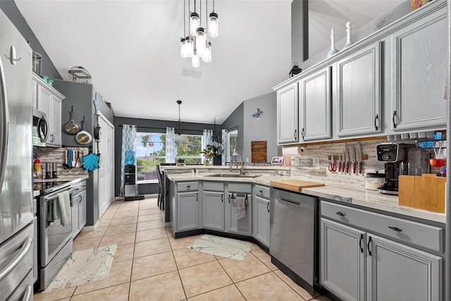 544 Lake Sumner Dr, Groveland, FL 34736 - kitchen with appliances with stainless steel finishes, gray cabinetry, decorative backsplash, a peninsula, and lofted ceiling