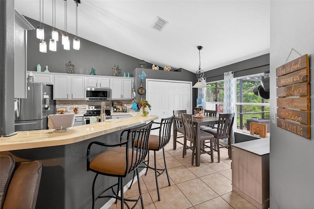 544 Lake Sumner Dr, Groveland, FL 34736 - kitchen with appliances with stainless steel finishes, decorative backsplash, white cabinets, vaulted ceiling, and light tile patterned floors