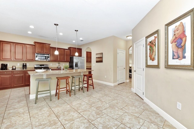 4123 Oaktree Dr, Davenport, FL 33837 - kitchen with stainless steel appliances, arched walkways, light tile patterned flooring, a breakfast bar area, and a center island with sink