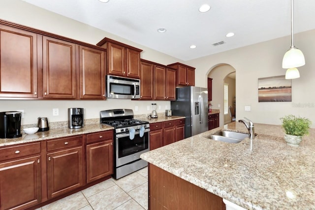 4123 Oaktree Dr, Davenport, FL 33837 - kitchen with appliances with stainless steel finishes, arched walkways, light tile patterned flooring, hanging light fixtures, and light stone countertops