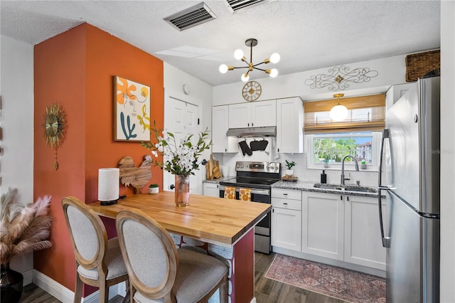 1100 E Caroline St Unit 204, Tavares, FL 32778 - kitchen with stainless steel appliances, dark wood finished floors, white cabinets, under cabinet range hood, and a textured ceiling