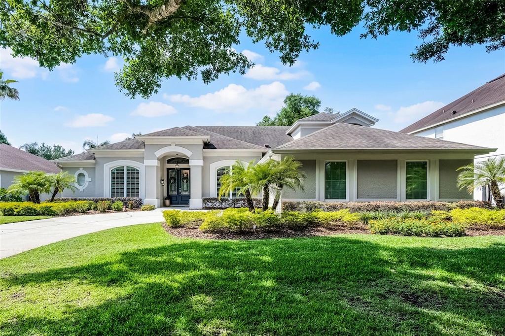 8122 Westminster Abbey Blvd, Orlando, FL 32835 - view of front of home with a front yard, stucco siding, a shingled roof, and driveway