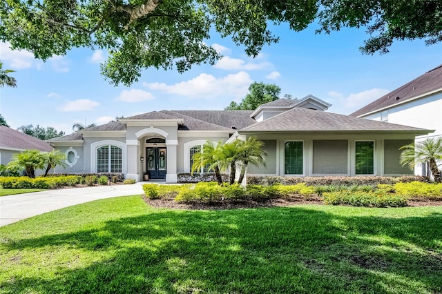 8122 Westminster Abbey Blvd, Orlando, FL 32835 - view of front of home with a front yard, stucco siding, a shingled roof, and driveway