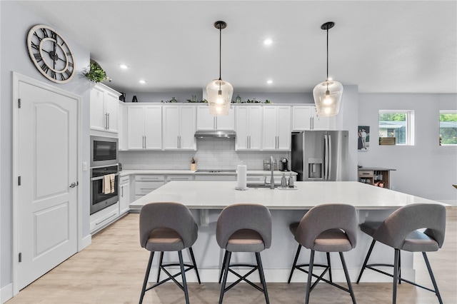 17676 Passionflower Cir, Clermont, FL 34714 - kitchen with stainless steel appliances, tasteful backsplash, under cabinet range hood, light countertops, and a kitchen island with sink