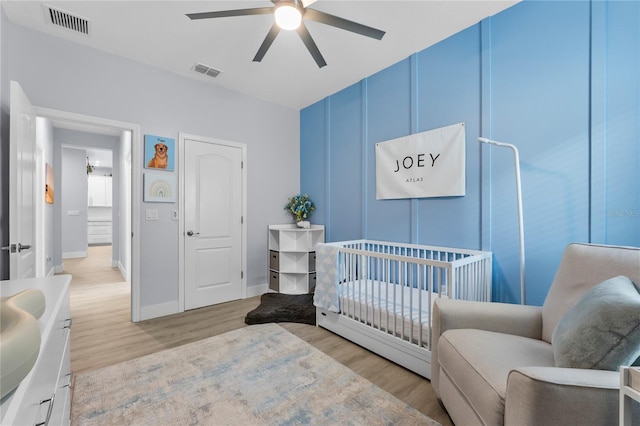 17676 Passionflower Cir, Clermont, FL 34714 - bedroom with light wood-style floors, a nursery area, a decorative wall, and a ceiling fan