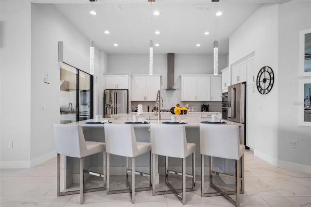 1526 Euston Dr, Reunion, FL 34747 - kitchen featuring light marble finish floors, stainless steel fridge, wall chimney range hood, recessed lighting, and white cabinets