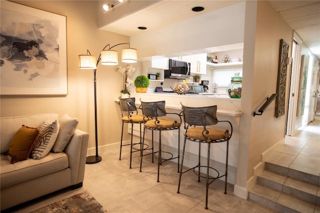 4203 Fairway Run, Tampa, FL 33618 - kitchen featuring stainless steel microwave, a breakfast bar area, light tile patterned floors, and open shelves