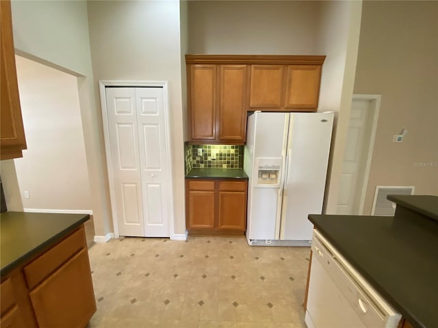 1227 Juniper Hammock St, Winter Garden, FL 34787 - kitchen with white appliances, dark countertops, tasteful backsplash, and brown cabinetry