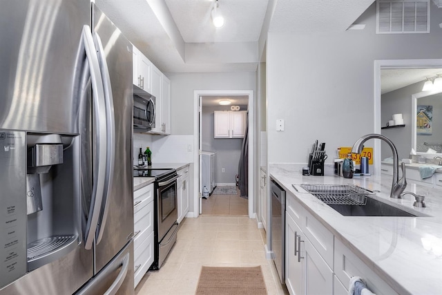 12204 Wild Iris Way Unit 108, Orlando, FL 32837 - kitchen featuring appliances with stainless steel finishes, white cabinets, light stone counters, light tile patterned flooring, and a textured ceiling