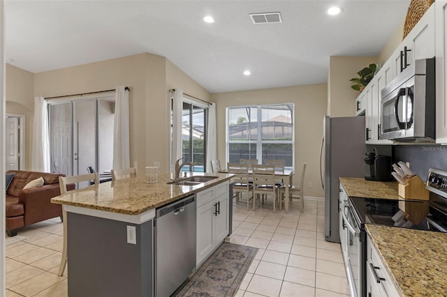 2222 Wyndham Palms Way, Kissimmee, FL 34747 - kitchen with stainless steel appliances, light tile patterned flooring, white cabinets, an island with sink, and recessed lighting