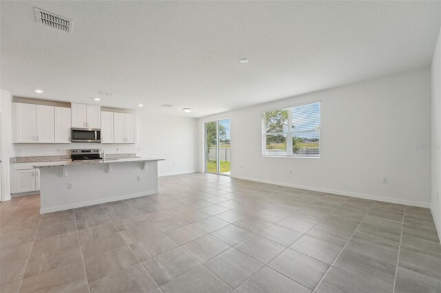 1349 Oak Valley Dr, Auburndale, FL 33823 - kitchen with stainless steel microwave, open floor plan, an island with sink, electric range, and light tile patterned flooring