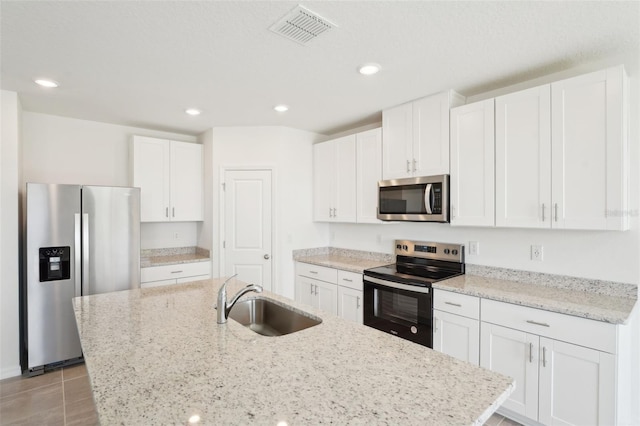 1349 Oak Valley Dr, Auburndale, FL 33823 - kitchen with appliances with stainless steel finishes, white cabinets, an island with sink, recessed lighting, and light stone countertops