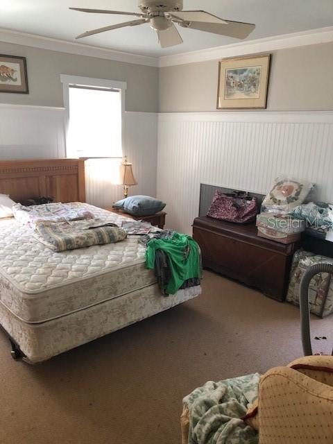 310 W Lake Ave, Auburndale, FL 33823 - bedroom with wainscoting, ornamental molding, carpet, and ceiling fan