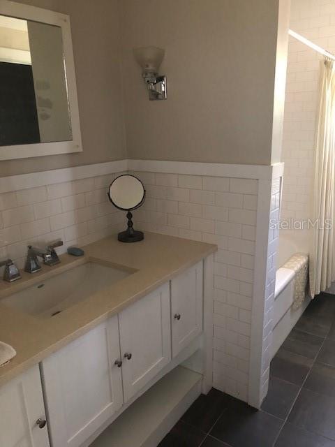 310 W Lake Ave, Auburndale, FL 33823 - full bathroom featuring tile walls, vanity, tile patterned flooring, shower / bath combo, and a wainscoted wall