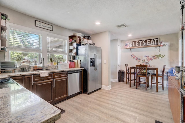 369 Bluff Lake Rd, Mascotte, FL 34753 - kitchen featuring stainless steel appliances, open shelves, healthy amount of natural light, light wood-style floors, and a textured ceiling