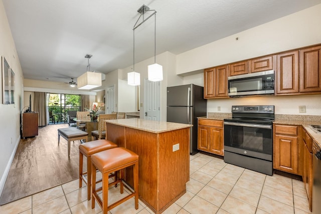 12527 Floridays Resort Dr Unit E104, Orlando, FL 32821 - kitchen with appliances with stainless steel finishes, brown cabinets, a kitchen island, open floor plan, and light tile patterned floors