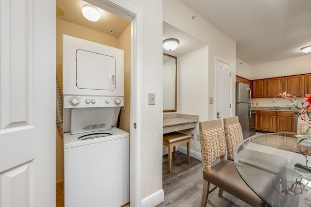 12527 Floridays Resort Dr Unit E104, Orlando, FL 32821 - laundry area featuring stacked washing machine and dryer and light wood-style flooring