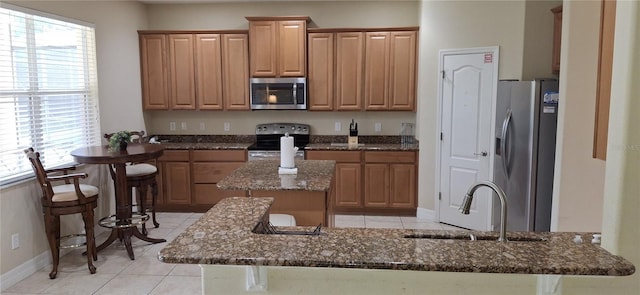 844 Suffolk Pl, Davenport, FL 33896 - kitchen featuring appliances with stainless steel finishes, dark stone countertops, a center island, light tile patterned floors, and a peninsula