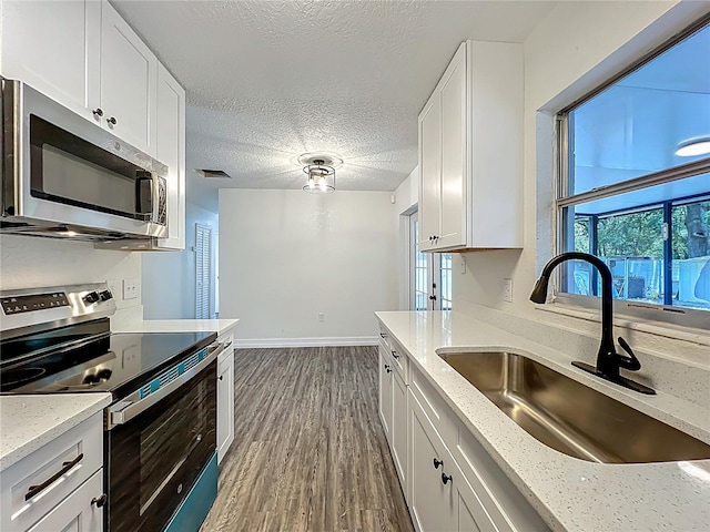 2109 Hartwell Ave, Sanford, FL 32771 - kitchen with appliances with stainless steel finishes, white cabinets, dark wood-style floors, a textured ceiling, and light stone counters