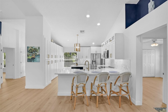 189 Blackstone Creek Rd, Groveland, FL 34736 - kitchen with appliances with stainless steel finishes, a peninsula, light countertops, backsplash, and white cabinetry