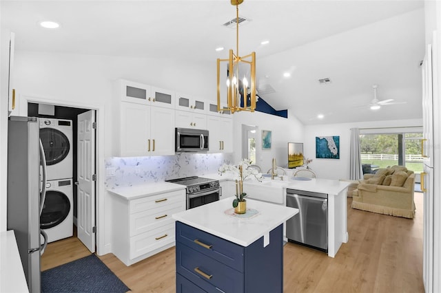 189 Blackstone Creek Rd, Groveland, FL 34736 - kitchen featuring appliances with stainless steel finishes, stacked washing machine and dryer, a peninsula, light countertops, and white cabinetry