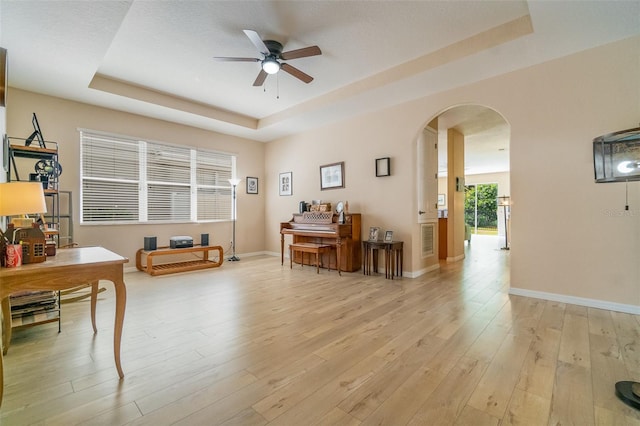 3896 Esplanade Ave, Port Orange, FL 32129 - living area featuring a raised ceiling, arched walkways, a ceiling fan, and light wood-style floors