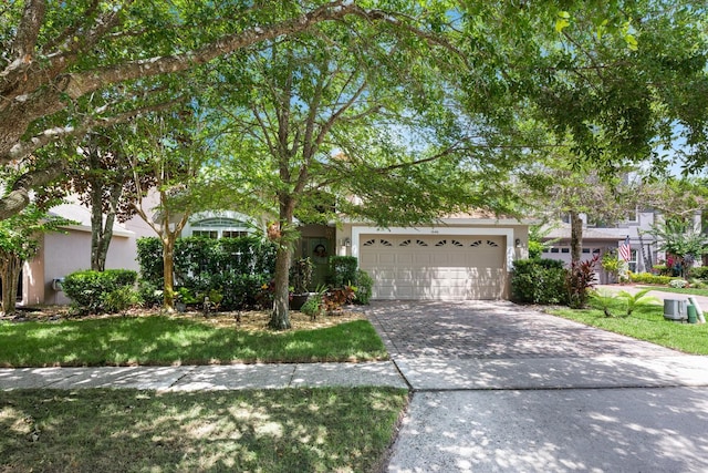 1646 Song Sparrow Ct, Sanford, FL 32773 - view of property hidden behind natural elements with driveway, an attached garage, stucco siding, and a front lawn