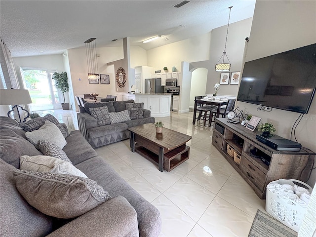 150 Barefoot Beach Way, Kissimmee, FL 34746 - living room featuring arched walkways, a textured ceiling, light tile patterned floors, and high vaulted ceiling