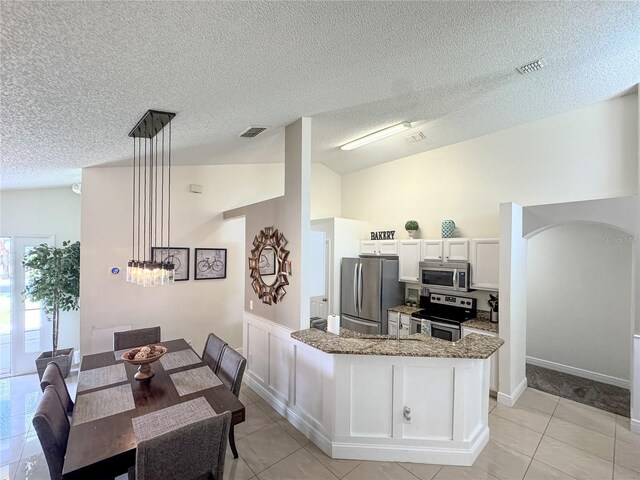 150 Barefoot Beach Way, Kissimmee, FL 34746 - kitchen featuring stainless steel appliances, stone counters, light tile patterned flooring, white cabinets, and a textured ceiling