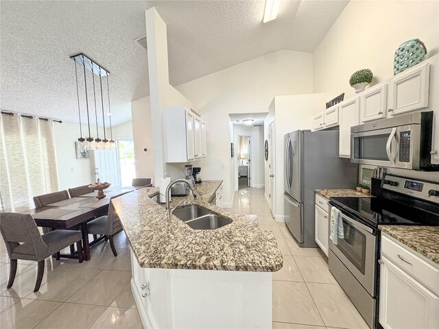 150 Barefoot Beach Way, Kissimmee, FL 34746 - kitchen with stainless steel appliances, a textured ceiling, lofted ceiling, light stone countertops, and light tile patterned floors