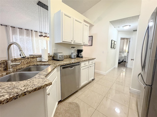 150 Barefoot Beach Way, Kissimmee, FL 34746 - kitchen with stainless steel appliances, a textured ceiling, white cabinetry, light stone counters, and light tile patterned floors