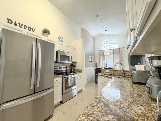 150 Barefoot Beach Way, Kissimmee, FL 34746 - kitchen featuring stainless steel appliances, a textured ceiling, lofted ceiling, light tile patterned floors, and white cabinetry