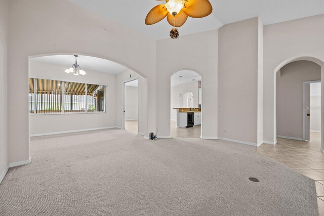 5339 Pond Crossing Pl, Leesburg, FL 34748 - unfurnished living room with arched walkways, a ceiling fan, tile patterned floors, carpet, and a high ceiling