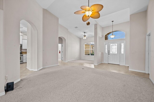 5339 Pond Crossing Pl, Leesburg, FL 34748 - foyer entrance with arched walkways, a ceiling fan, light carpet, and a towering ceiling